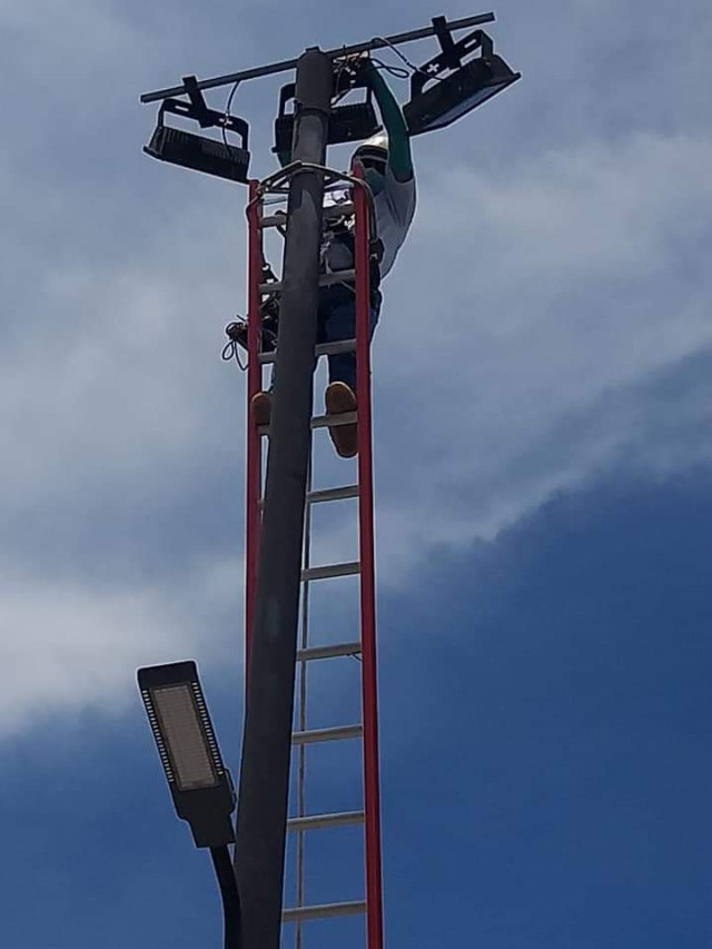 Hombre laborando en una luminaria en trabajo en altura.