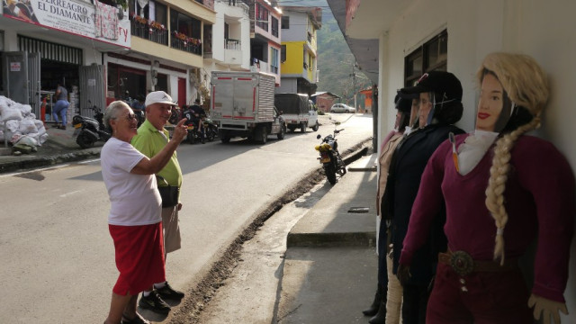 Pareja se detiene en la calle a ver muñecos de trapo exhibidos en un andén en Arauca (Palestina).