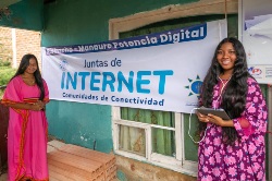 Dos mujeres de la comunidad Wayuu posan frente a pasacalle que promueve el programa internet social del Gobierno colombiano.