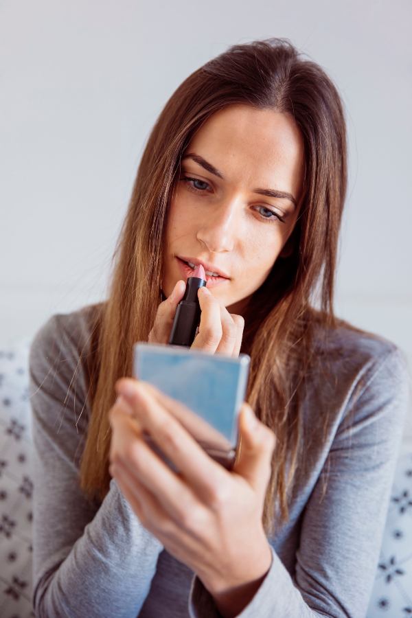 Joven se aplica producto en los labios.