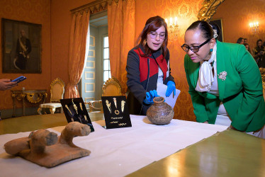 Fotografía cedida por la Cancillería de Colombia donde se observa a dos mujeres mientras analizan algunas de las 16 piezas precolombinas procedentes de colecciones privadas de Suiza y Nueva Zelanda recuperadas por el Gobierno de Colombia, este martes en Bogotá.