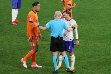 El árbitro Anthony Taylor conversa con el capitán de Francia Antoine Griezmann (d) y el capitán de Países Bajos Virgil van Dijk (i) mientras esperan la decisión del VAR que luego anuló un gol a los naranjas durante el partido de fútbol del Grupo D de la Eurocopa 2024 entre Países Bajos y Francia, en Leipzig, Alemania.