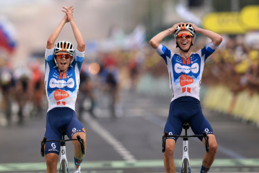 El ciclista francés Romain Bardet (d) del equipo DSM reacciona mientras cruza la línea de meta junto a su compañero de equipo, el ciclista holandés Frank van den Broek (i), para ganar la primera etapa de la carrera ciclista Tour de Francia 2024 de 206 km desde Florencia hasta Rimini (Italia).
