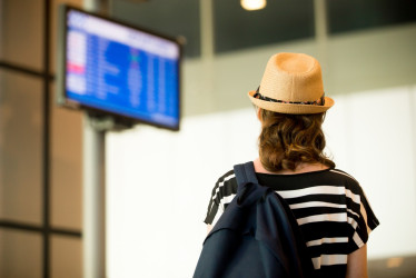 mujer viendo pantalla de vuelos en aeropuerto