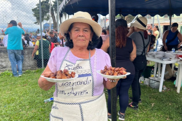 Estelia Vélez levanta dos platos de fritanga que ofrece a los más necesitados en Anserma.