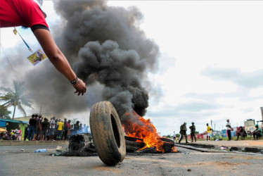 Un hombre coloca un neumático en una barricada en llamas en una calle de Maputo durante una protesta postelectoral por los controvertidos resultados de las elecciones de octubre.