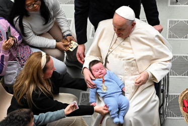 El Papa Francisco sostiene a un bebé mientras saluda a los fieles durante su audiencia general semanal en la Sala Pablo VI, en la Ciudad del Vaticano, este miércoles.